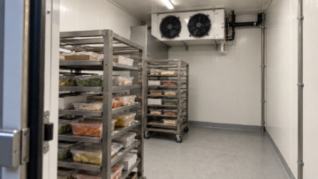 Blast freezer airflow arrangement with loaded stainless-steel racks, supply plenum and ceiling-mounted evaporators